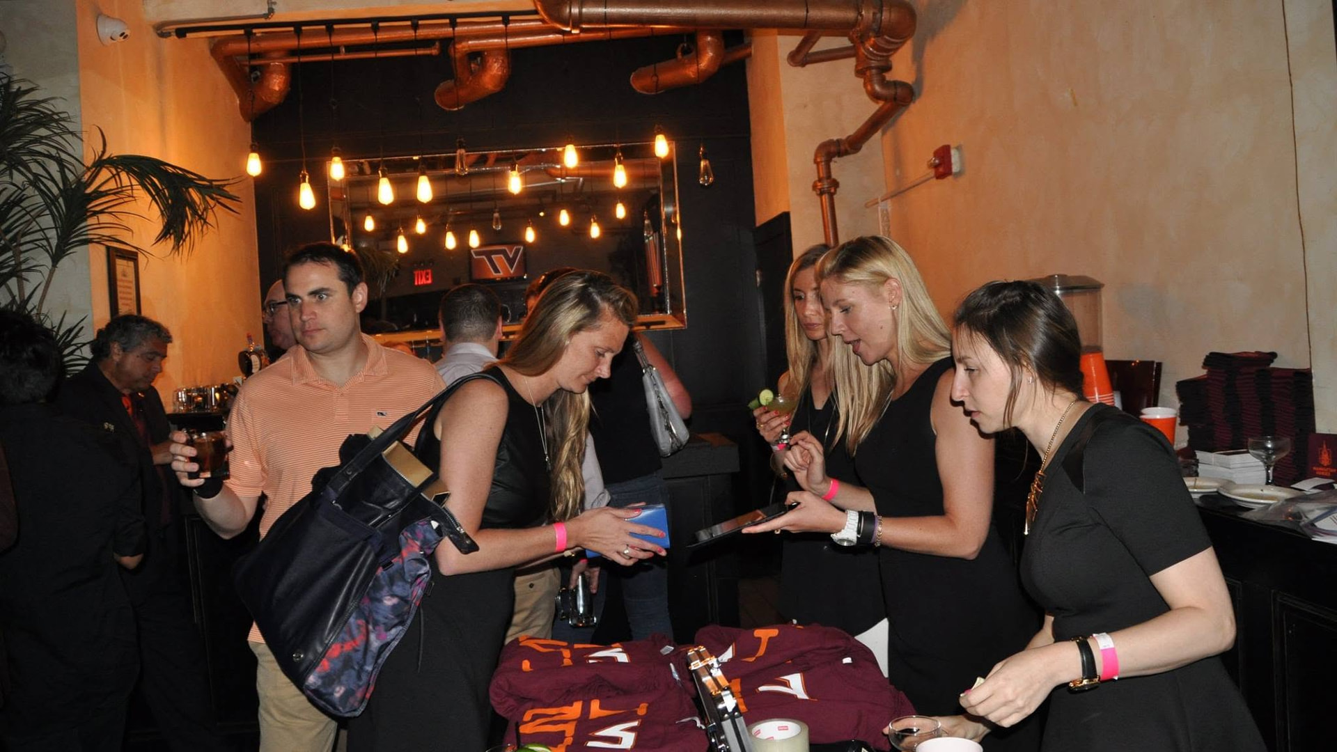 Attendees gathered around Virginia Tech merchandise at a 2016 Manhattan Hokies event