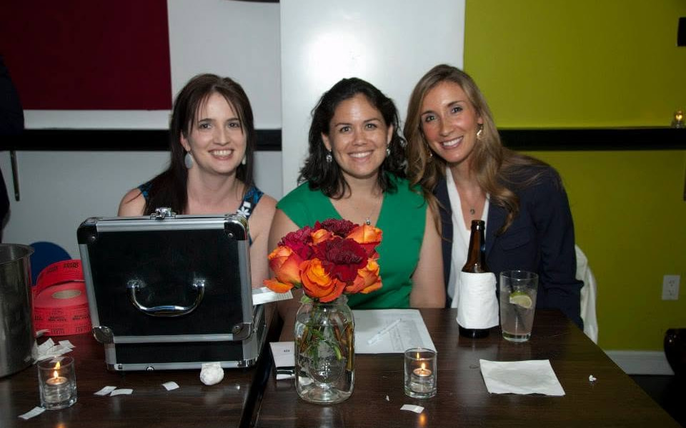 Three attendees seated behind an event table at a 2013 Manhattan Hokies gathering