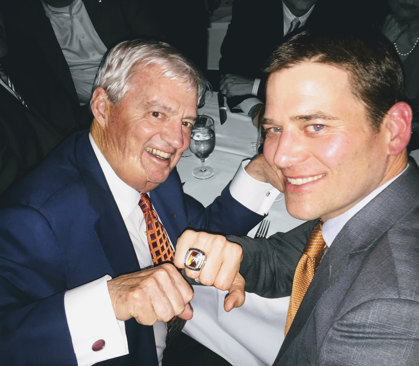 Two Virginia Tech community members showing a championship ring at a chapter gathering