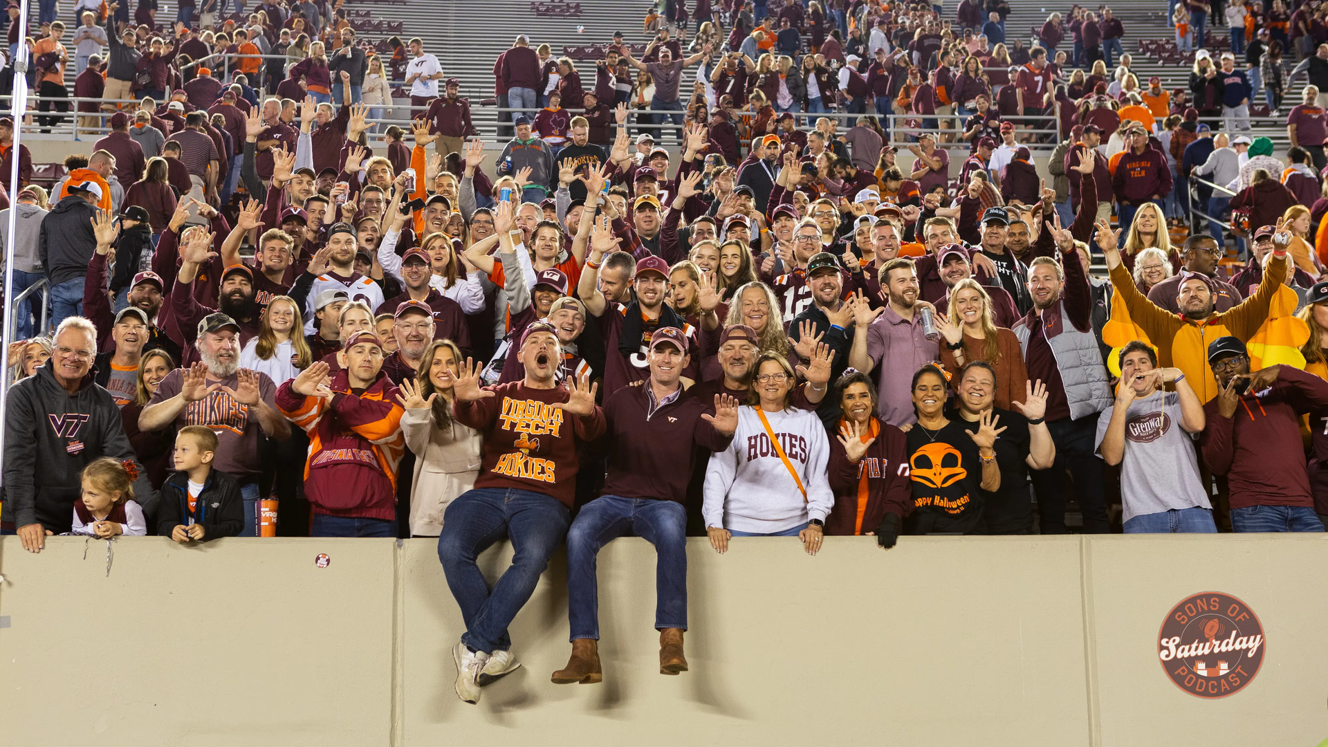 A large crowd of Virginia Tech fans in a football stadium with the Sons of Saturday mark