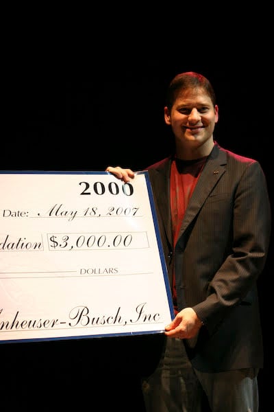 Steve Hole presenting a ceremonial donation check onstage at Maroon Effect